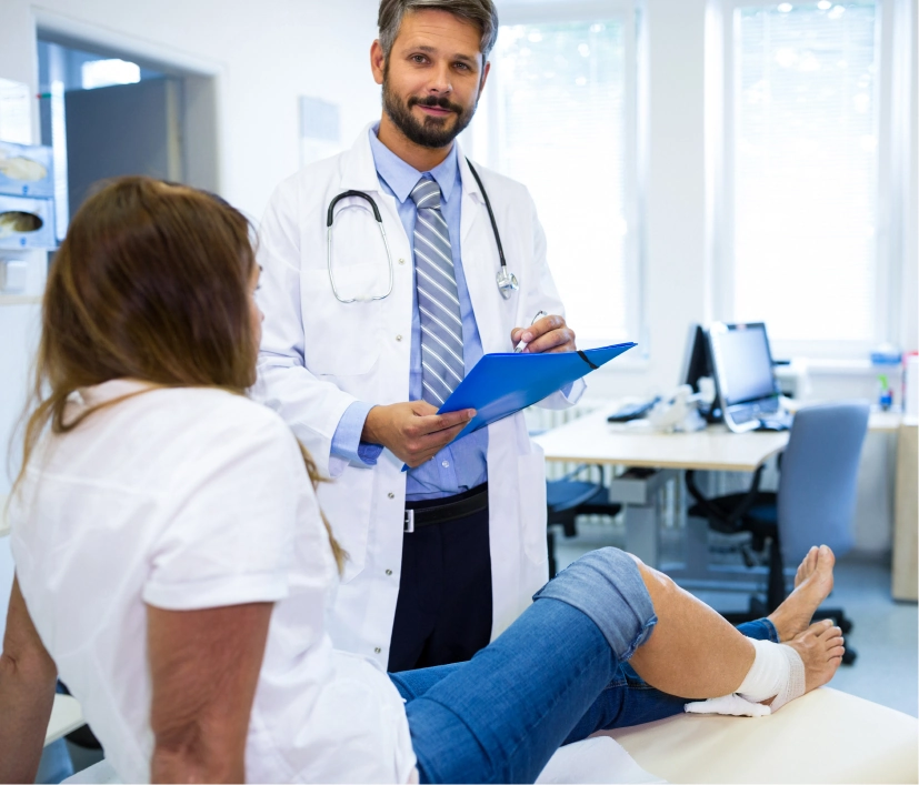 Podiatrist with a clipboard consulting a patient with an injured foot in a podiatry clinic